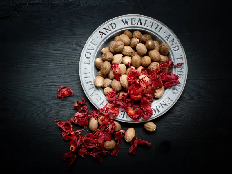 Whole nutmeg and crimson mace arils in a metal dish