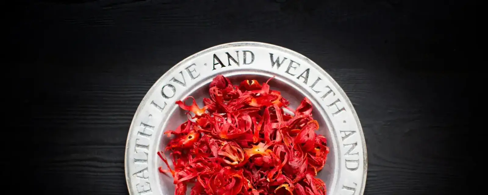 Dried crimson mace arils in a metal dish on dark wood