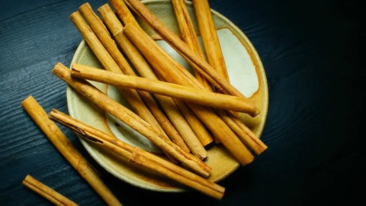 Ceylon cinnamon quills on a ceramic plate against a dark surface